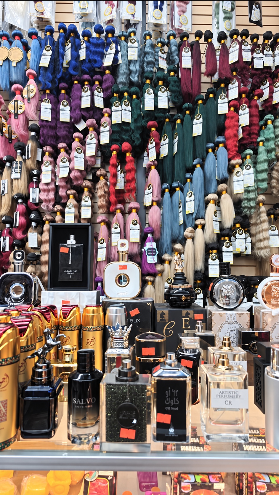 Colorful hair bundles above Royal Beauty’s fragrance display